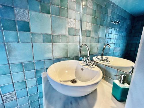 a bathroom with a white sink and a blue tiled wall at Traditional house in Koskinou in Koskinou