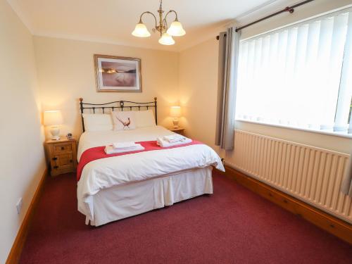 sypialnia z dużym łóżkiem z czerwonym dywanem w obiekcie Nursery Cottage w mieście Louth