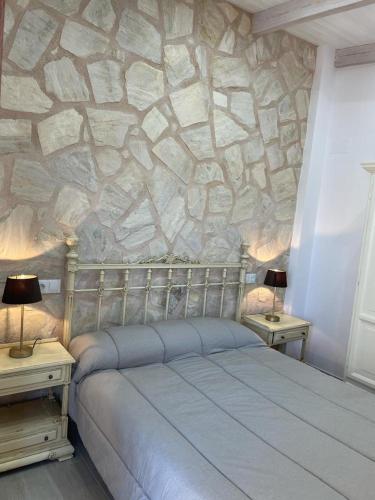 a bedroom with a stone wall with a bed and two tables at Vivienda turística Las 3 A in El Ojuelo