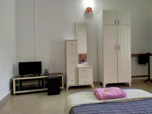 1 dormitorio con 1 cama, TV y vestidor en MELATI INN en Kajang