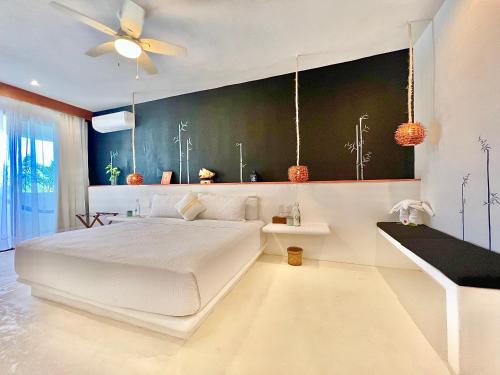 a bedroom with a white bed and a ceiling fan at Hotel Casa HX - Adults Only in Holbox Island
