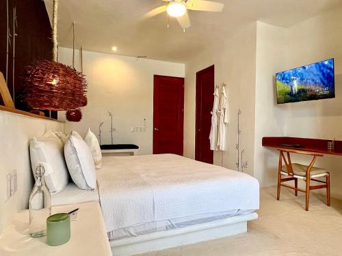 a bedroom with a white bed with a ceiling fan at Hotel Casa HX - Adults Only in Holbox Island