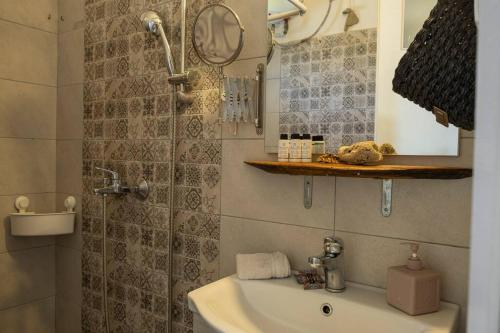 a bathroom with a sink and a shower with a mirror at Odysseas Pelion House in Kalamaki