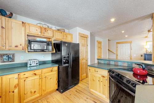 a kitchen with a black refrigerator and wooden cabinets at Sunset Chalet in Tabernash