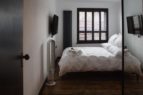 1 dormitorio con cama, ventana y espejo en •MangoHausLondon• •airconditioned•garden•fire pit•, en Londres