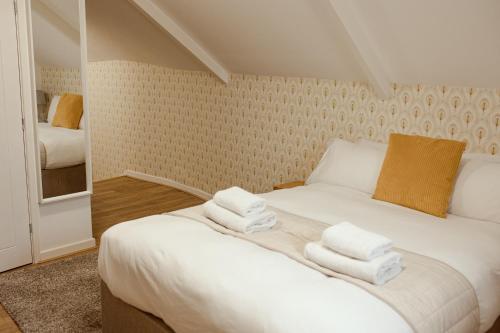 1 dormitorio con 1 cama blanca grande y toallas. en JT Abergwaun hotel en Fishguard