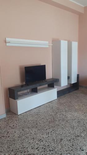 una sala de estar con TV en un centro de entretenimiento blanco en Villa Ginevra en Paestum