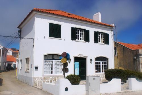 a white house with black shuttered windows at Foz Surfcamp in Foz do Arelho