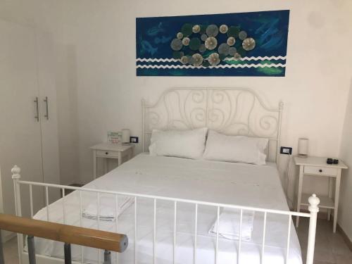 ein Schlafzimmer mit einem weißen Bett und einem Gemälde an der Wand in der Unterkunft Rio Rest Apartments in Riomaggiore