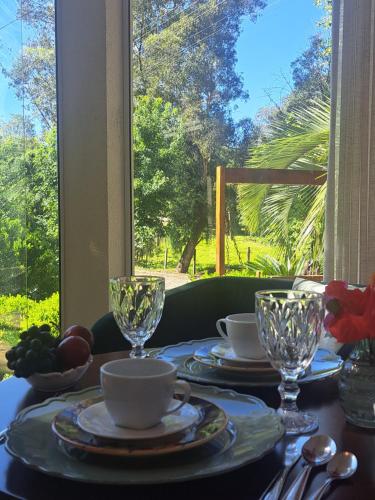 a table with plates and cups on a table with a window at Locanda Montecielo Pousada Boutique - Vale dos Vinhedos in Bento Gonçalves