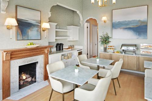 a kitchen with two tables and a fireplace at Green Gables Inn, A Four Sisters Inn in Pacific Grove