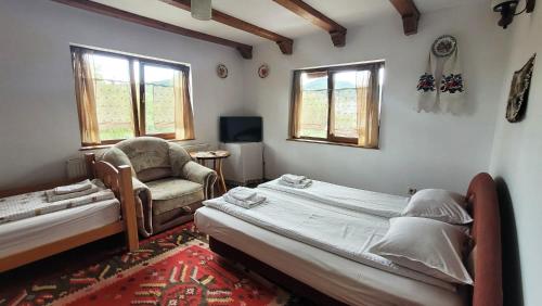 - une chambre avec 2 lits, une chaise et des fenêtres dans l'établissement Pensiunea Ardelean, à Vadu Izei
