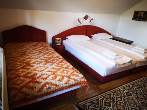 a bedroom with two beds and a rug at Pensiunea Ardelean in Vadu Izei