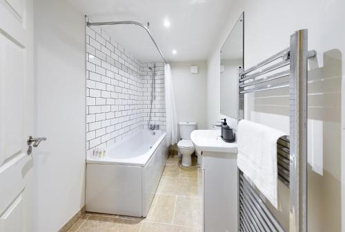 a bathroom with a tub and a toilet and a sink at Redhill town centre apartments by Livingo in Redhill