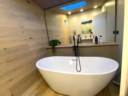 a white bath tub in a bathroom with wooden walls at The Oak house - Designers private Northern lights geothermal Villa in Mosfellsbær