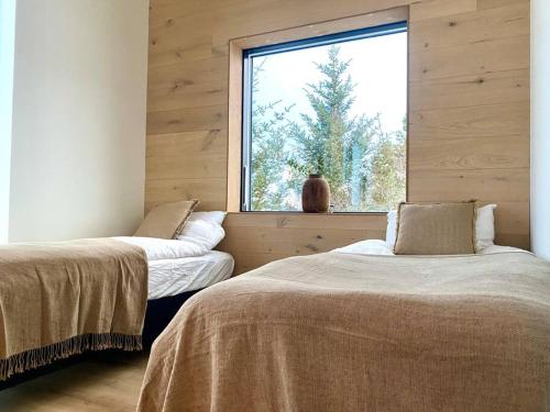 two beds in a room with a window at The Oak house - Designers private Northern lights geothermal Villa in Mosfellsbær