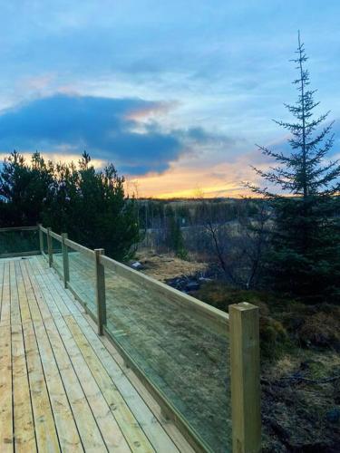 a wooden boardwalk with a fence and a pine tree at The Oak house - Designers private Northern lights geothermal Villa in Mosfellsbær