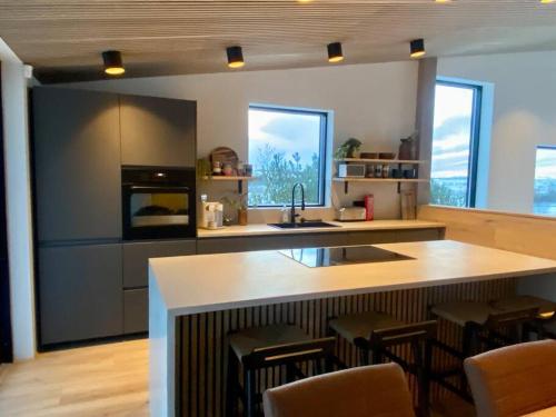a kitchen with a large island with chairs in it at The Oak house - Designers private Northern lights geothermal Villa in Mosfellsbær