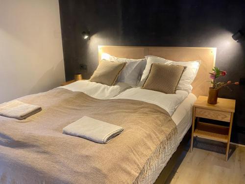 a large bed with white sheets and pillows on it at The Oak house - Designers private Northern lights geothermal Villa in Mosfellsbær