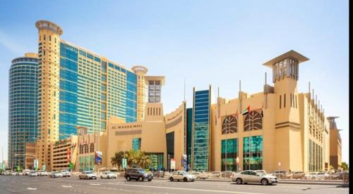 a large building with cars parked in a parking lot at Corniche Street - Luxury Room in Abu Dhabi