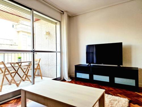 a living room with a flat screen tv and a table at Chabós Plaza España - Charming Flats in Vigo