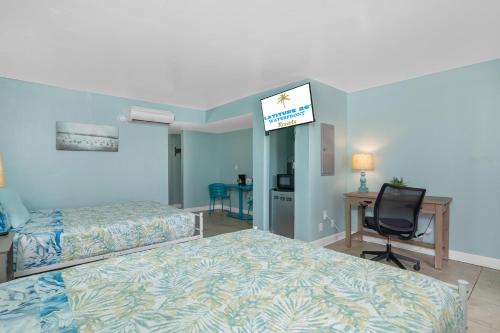 a bedroom with two beds and a desk and a chair at Latitude 26 Waterfront Resort and Marina in Fort Myers Beach
