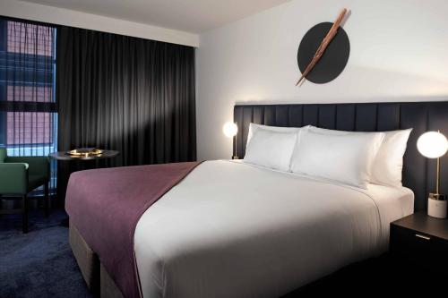 a hotel room with a large bed and a chair at Midnight Hotel, Autograph Collection in Canberra