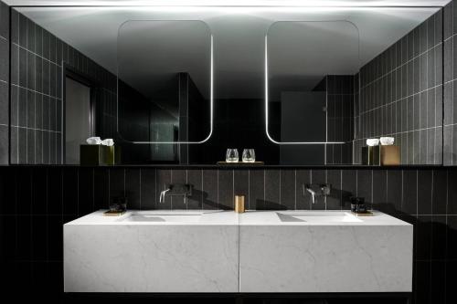 a bathroom with two sinks and a mirror at Midnight Hotel, Autograph Collection in Canberra