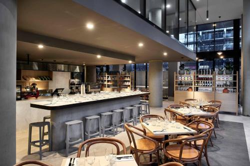 a restaurant with tables and chairs and a bar at Midnight Hotel, Autograph Collection in Canberra