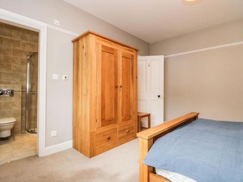 - une chambre avec un lit et une armoire en bois dans l'établissement Connie's Cottage, à Ambleside