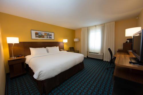 a hotel room with a large bed and a television at Fairfield Inn & Suites Burlington in Burlington