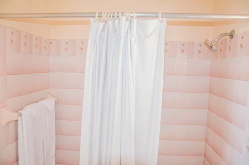 - un rideau de douche blanc dans une salle de bains rose dans l'établissement Urban Apartments, à Runaway Bay