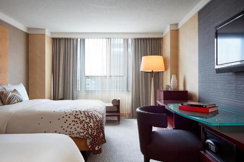 コロンバスにあるRenaissance Columbus Downtown Hotelのベッド、デスク、テレビが備わるホテルルームです。