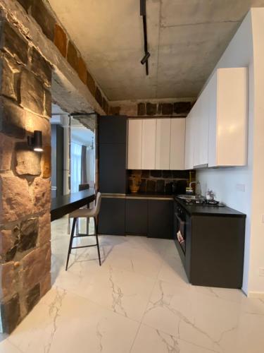 - une cuisine avec des placards blancs et un mur en pierre dans l'établissement Dark Apartment, à Erevan