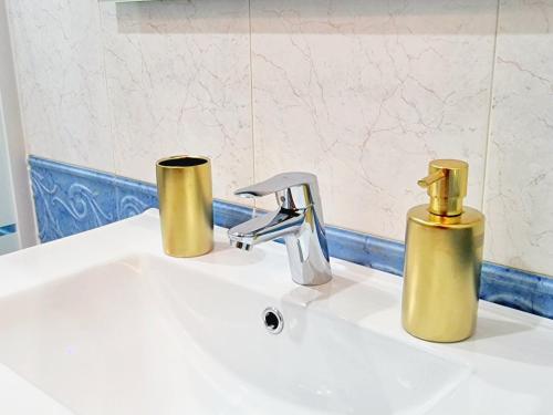 a bathroom sink with two gold containers on it at Chabós Plaza España - Charming Flats in Vigo
