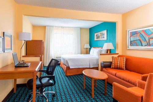 a hotel room with a bed and a couch and a desk at Fairfield Inn Muncie in Muncie