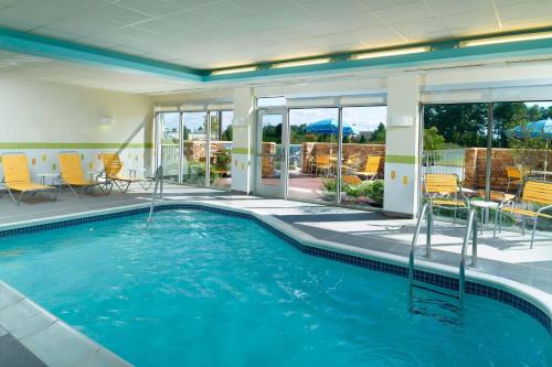 a swimming pool with chairs and tables in a building at Fairfield Inn & Suites by Marriott Fayetteville North in Fayetteville