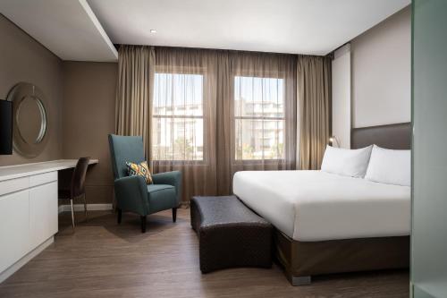 a hotel room with a bed and a chair at Protea Hotel by Marriott Cape Town Waterfront Breakwater Lodge in Cape Town