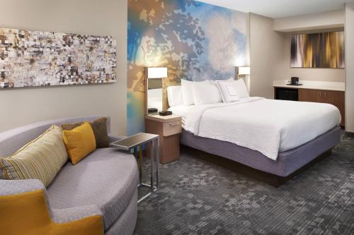 a hotel room with a bed and a couch at Courtyard Cincinnati Covington in Covington