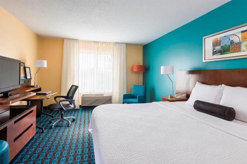 a hotel room with a bed and a flat screen tv at Fairfield Inn & Suites Naperville/Aurora in Naperville