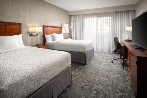 a hotel room with two beds and a flat screen tv at Courtyard by Marriott Phoenix Mesa in Mesa
