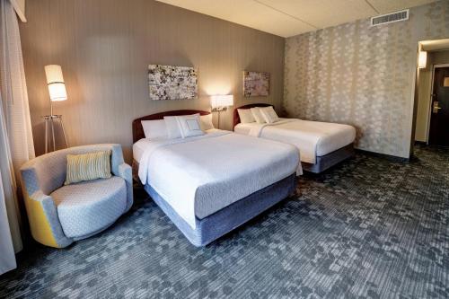 a hotel room with two beds and a chair at Courtyard Wausau in Wausau