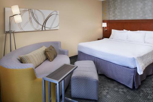 a hotel room with a bed and a chair at Courtyard by Marriott Rockford in Rockford