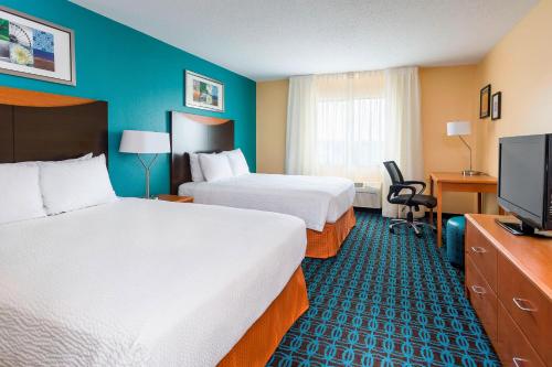 a hotel room with two beds and a flat screen tv at Fairfield Inn & Suites Jackson in Jackson