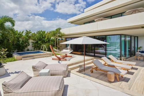 a house with a patio with chairs and an umbrella at The St. Regis Kanai Resort, Riviera Maya in Playa del Carmen