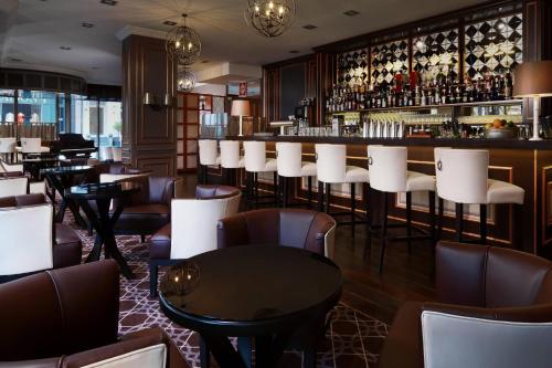 a restaurant with a bar with white chairs and tables at Hamburg Marriott Hotel in Hamburg