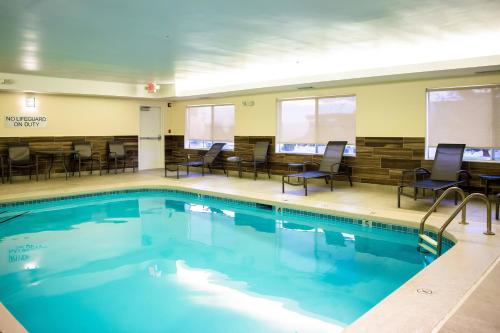 una piscina con sedie e tavoli in un edificio di Fairfield Inn & Suites Fredericksburg a Fredericksburg