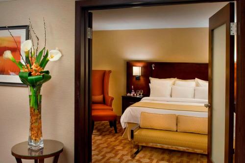 a hotel room with a bed and a vase of flowers at Trumbull Marriott Shelton in Trumbull