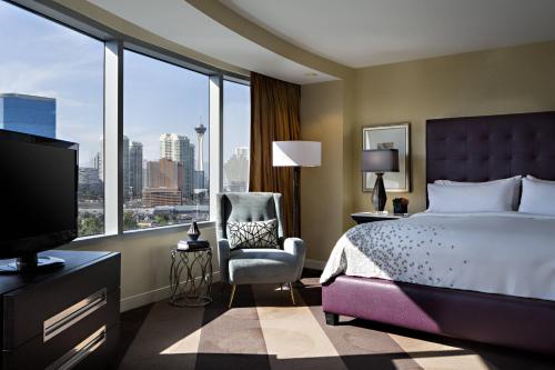 a bedroom with a bed and a chair and a large window at Renaissance Las Vegas Hotel in Las Vegas