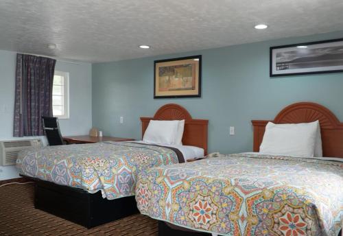two beds in a hotel room with blue walls at Bestway Inn in Muncie